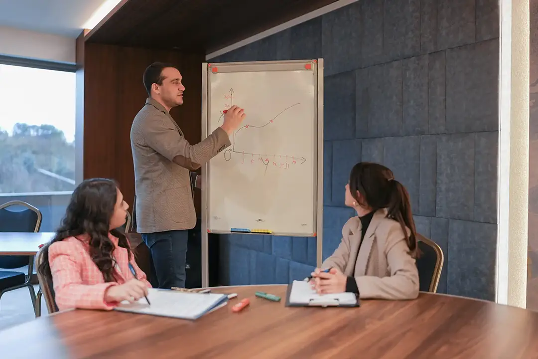A man confidently presents on a whiteboard.